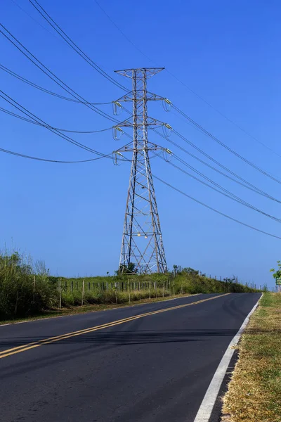 Electric power transmission towers, on the side of the highway in perspective