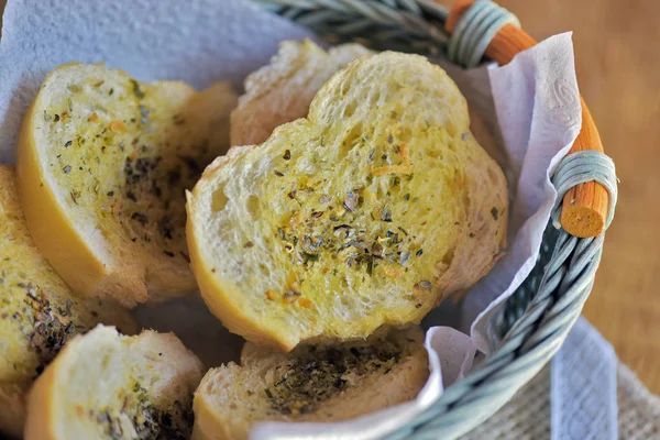 Portion of appetizer made from bread seasoned with olive oil and fine herbs, in blue wicker basket