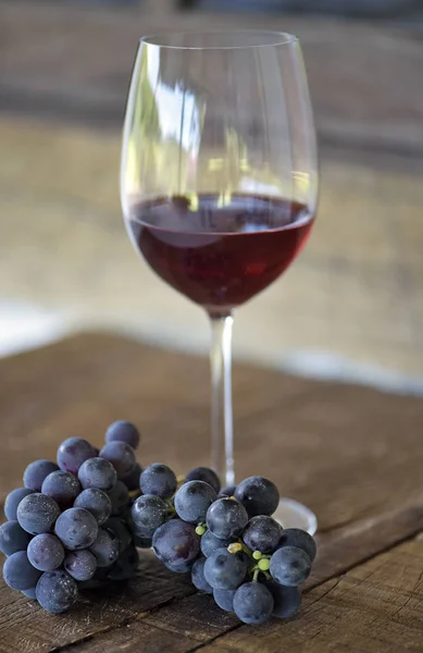 Glass of red wine and grape bunch on rustic wooden table