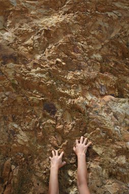 Close up view of female hands climbing on rocky cliff clipart