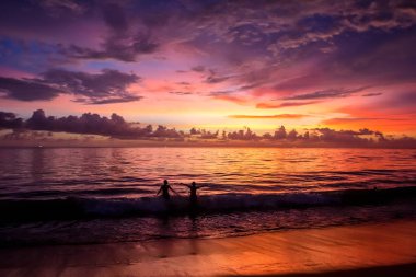 Eğleniyor denizde günbatımı sırasında insan siluetleri