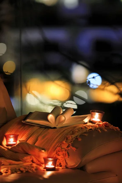 book with heart shaped pages and burning candles on armchair
