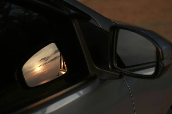 close up shot of vehicle mirror with reflection of sunset sky