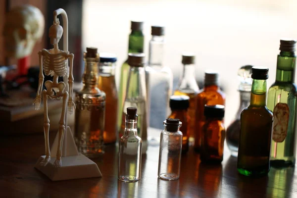 Various vintage medicine bottles and skeleton toy on table