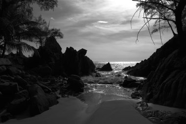 Deniz ve kayalık sahil, siyah ve beyaz üzerinde dramatik gökyüzü günbatımı