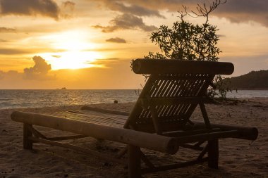 Gün batımı sırasında kum plajındaki ahşap şezlong