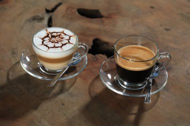 ahşap masa üzerinde kaşık ile cam bardak kapuçino ve espresso kahve 