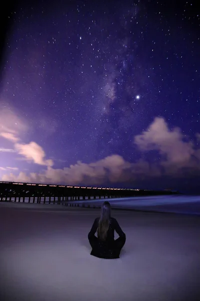 view of night sky with shining stars and woman on beach