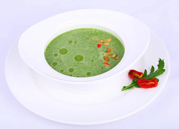 白いテーブルに緑色のスープと材料が入ったプレート — ストック写真