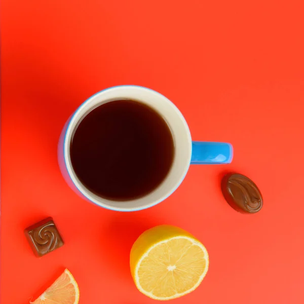 青いカップの紅茶 レモン スライス 赤い背景の上にチョコレート菓子 フラット横たわっていた トップ ビュー テキスト用の空き容量 — ストック写真