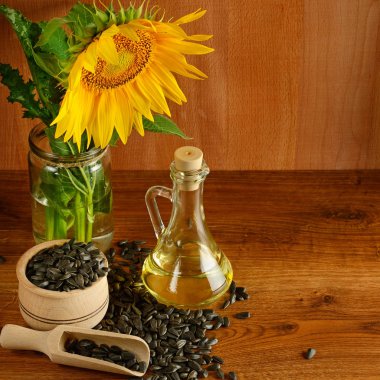 Tohumlar, yağ ve ayçiçekleri ahşap arka planda.