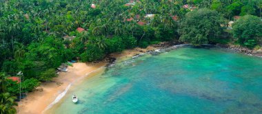Zengin mavi tonlarda deniz pelerini. Parlak turkuaz su ve tropikal bitki örtüsü olan güzel bir plaj. Geniş resim.