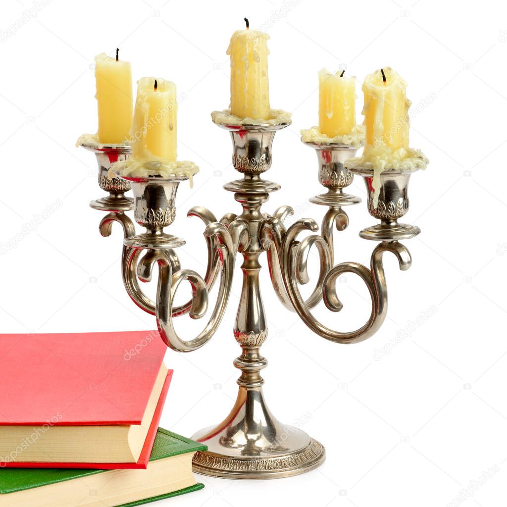 Old candlestick with candles and books isolated on white background.
