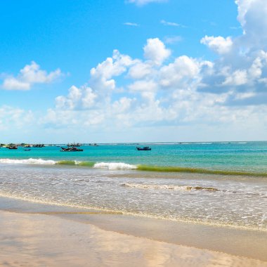 Geniş kumlu sahili ve berrak mavi suyu olan güzel bir deniz manzarası. Turizm ve açık hava aktiviteleri kavramı.