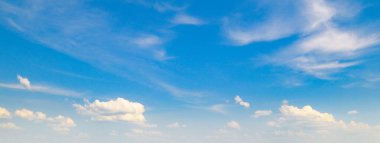 Açık mavi gökyüzünün panoramik görüntüsü çeşitli beyaz bulutlarla dolu. Geniş açı, açıklık, sükunet ve sonsuz boşluk hissi yakalar, metin için geniş kopya alanı ile..