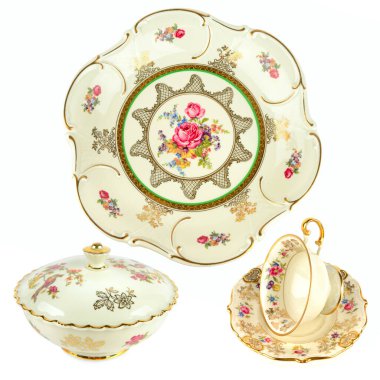 A trio of delicate vintage porcelain pieces, including a ruffled plate, lidded bowl, and teacup, with intricate floral and gold patterns. The items are isolated against a clean white background, highlighting their antique beauty.