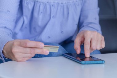 Çevrimiçi ödeme, kredi kartı tutan bir kadının elleri ve online alışveriş için akıllı telefonu kullanmak.