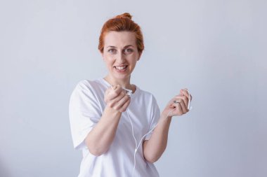 Kulaklıklı, beyaz arka planda kameraya bakıp gülen hoş, genç bir kız..