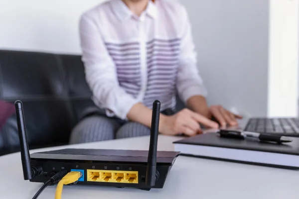 Ofiste dizüstü bilgisayar kullanan kablosuz yönlendirici ve kadın. router kablosuz geniş bant ev dizüstü bilgisayar telefon kablosuz telefon kavramı