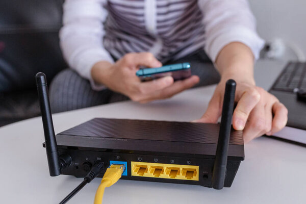 Close up of a wifi router and a woman using smartphone on living room at home ofiice
