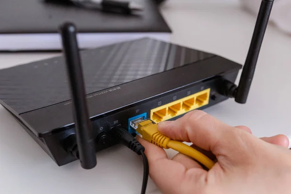  Kadın internet kablosunu yönlendiricinin prizine bağlıyor. Hızlı ve kablosuz internet konsepti