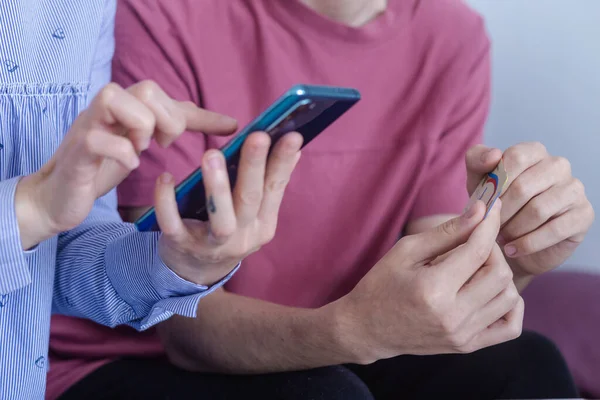 幸せな女性と男の手は テーブルの上に携帯電話やノートパソコン上の指を指す 良い関係 物事のインターネット オフィスで働くと議論しながら携帯電話に触れる2人の若いビジネスの人々 ストック写真