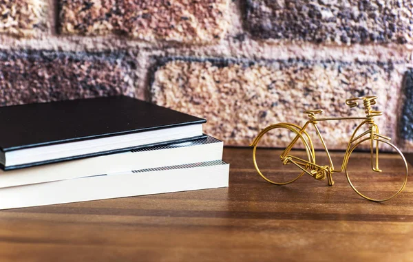 Three books on the wooden shelf with a golden bike