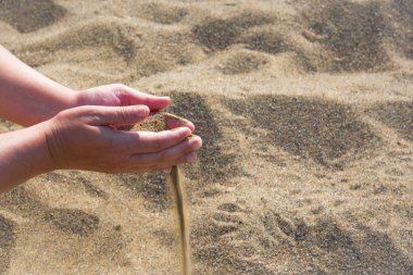 Kum parmaklarının arasından açık düşen avuç