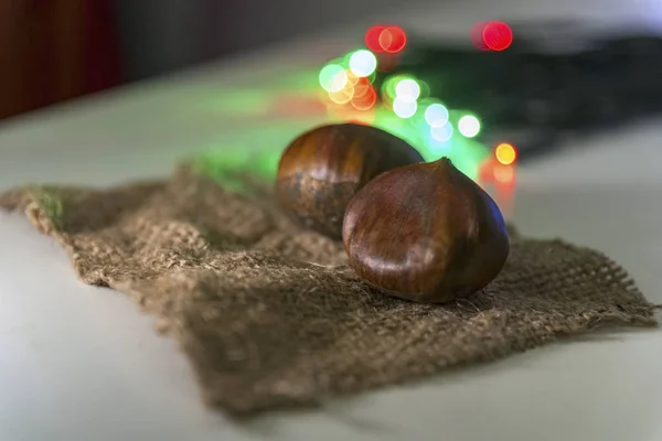 Kastanien Auf Einem Stück Hessischem Stoff Mit Weihnachtsbeleuchtung Nahaufnahme — Stockfoto