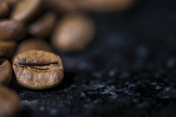Coffee beans on black marble background, macro photography, space for a logo picture or text