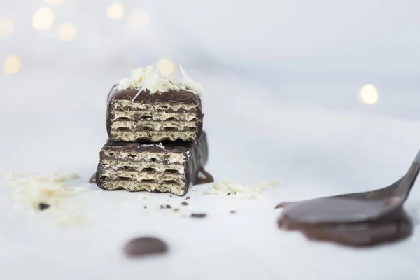 Wafer with melted bitter chocolate and white chocolate sprinkles, close up, bokeh lights background