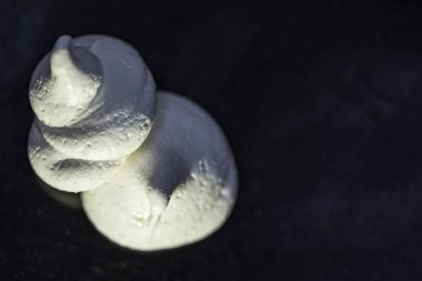 İki beyaz meringues izole, siyah bir zemin üzerine yakın çekim