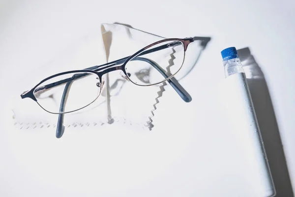 白い背景にクリーニングローションペンと白いクリーニングクロスを持つ眼鏡 クローズアップ — ストック写真
