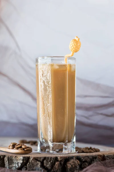 Beyaz arka planda sarı renkli kokteyl kaşığı olan soğuk latte bardağı, yakın plan, natürmort fotoğraf.