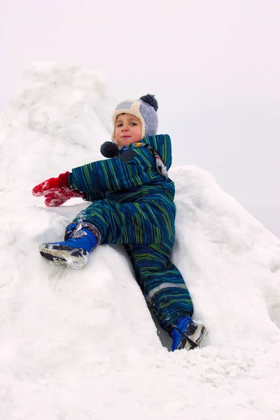 一个四岁的孩子 一个男孩 带着重要的风景爬上了雪山 他穿着冬衣 看着镜头 — 图库照片