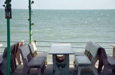 Taş masa sandalye sahilde bir gölgelik altında bir kafede ile. 