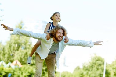 Genç adam uzanmış silah ve sırtında yaz günü parkta zevk küçük kızı