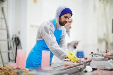 Tarafından deniz ürünleri işleme fabrika üretim hattında çalışan koruyucu üniformalı genç adam