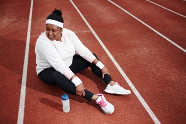 Stadyum yarış pisti tarafından plastik şişe ile oturan genç dinlendirici sporcumuz