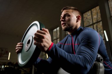 Kas atlet halter egzersiz sırasında ağır demir disk önünde tutan