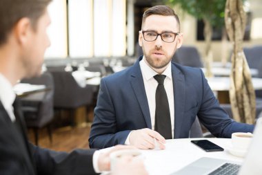 Zarif iş adamı ve iş arkadaşı tarafından tablo kafede oturan ve öğle yemeğinden sonra fikirlerini tartışıyor