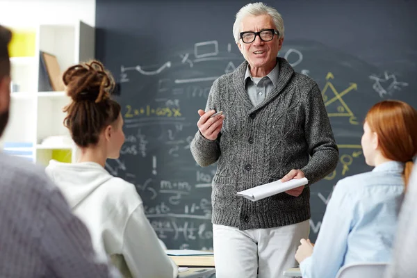 Experienced professor explaining his subject to group of students at lesson in college or university