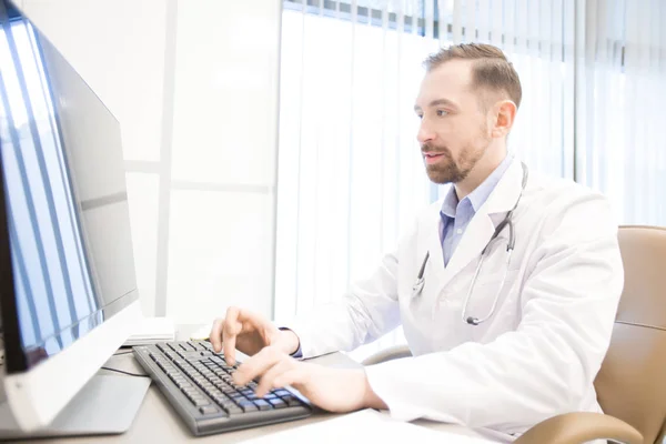 Ung Man Whitecoat Sitter Datorskärm Hans Skrivbord Kliniker Och Samråd — Stockfoto