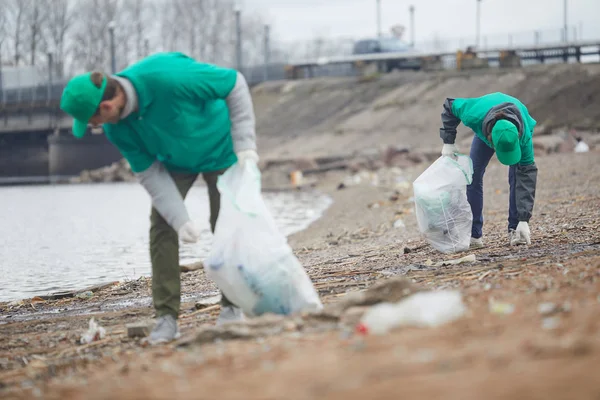 Młodzi Mężczyźni Ochrony Środowiska Przez Zbierając Śmieci Wybrzeża Przez Riverside — Zdjęcie stockowe