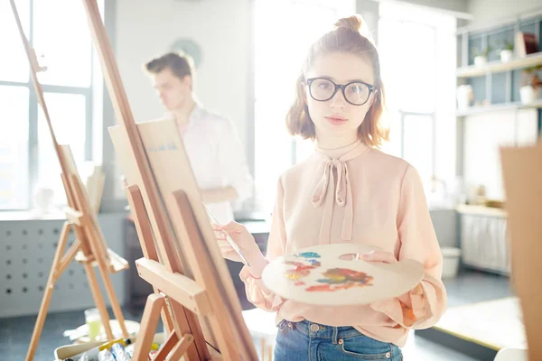 眼鏡やスマート カジュアルなカメラで見て芸術の近代学校の絵画の授業でかわいい女の子 — ストック写真