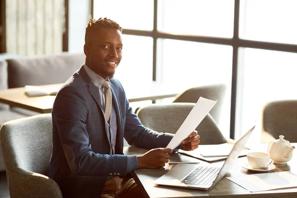 Joven Empresario Confiado Con Papel Financiero Mirándote Mientras Está Sentado — Foto de Stock