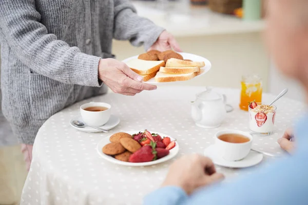 Mogen Kvinna Sätta Plattan Med Brödskivor Serveras Bord Med Desserter — Stockfoto