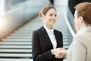 Onun yaşlı meslektaşım el sıkışma ve gülümseme tarafından tebrik başarılı genç iş kadını