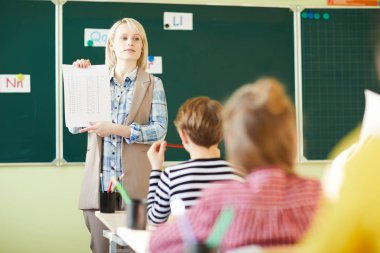 Kendine güvenen genç öğretmen İlköğretim öğrencilerin sınıfa kağıt dönem işaretleriyle gösterilen