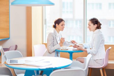 Pencere kafede oturan iki meşgul yöneticileri online bilgi tartışmak ve organize çalışır